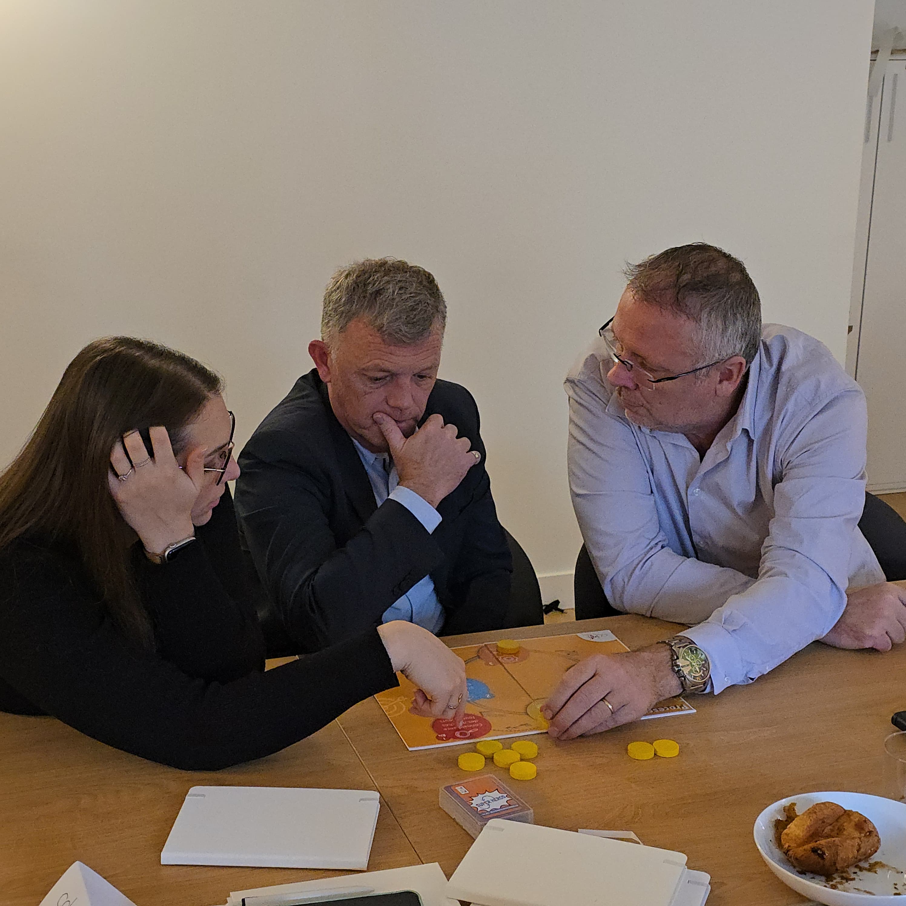 Trois participants penchés sur un plateau de jeu pendant une session de formation